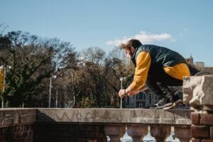 A young man performing parkour on an urban ledge, showcasing agility and strength.